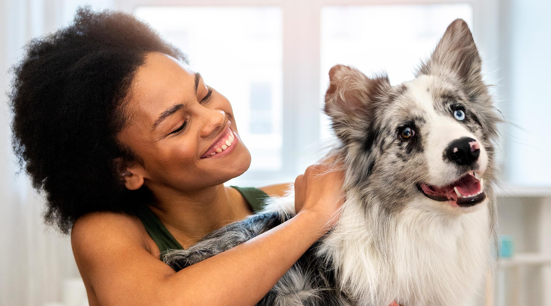 smiling-woman-petting-her-australian-shepherd-dog-1800x1000-1